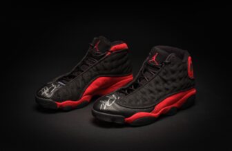 Black and red Air Jordan 13 basketball sneakers displayed on a dark background with signature Jumpman logo and sleek design